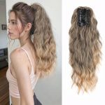 Falowany kucyk na klipsie w odcieniu złotego ombre – naturalne przejście od ciemniejszego brązu u nasady do ciepłego, złotego blondu na końcach. Długość – 40 cm.